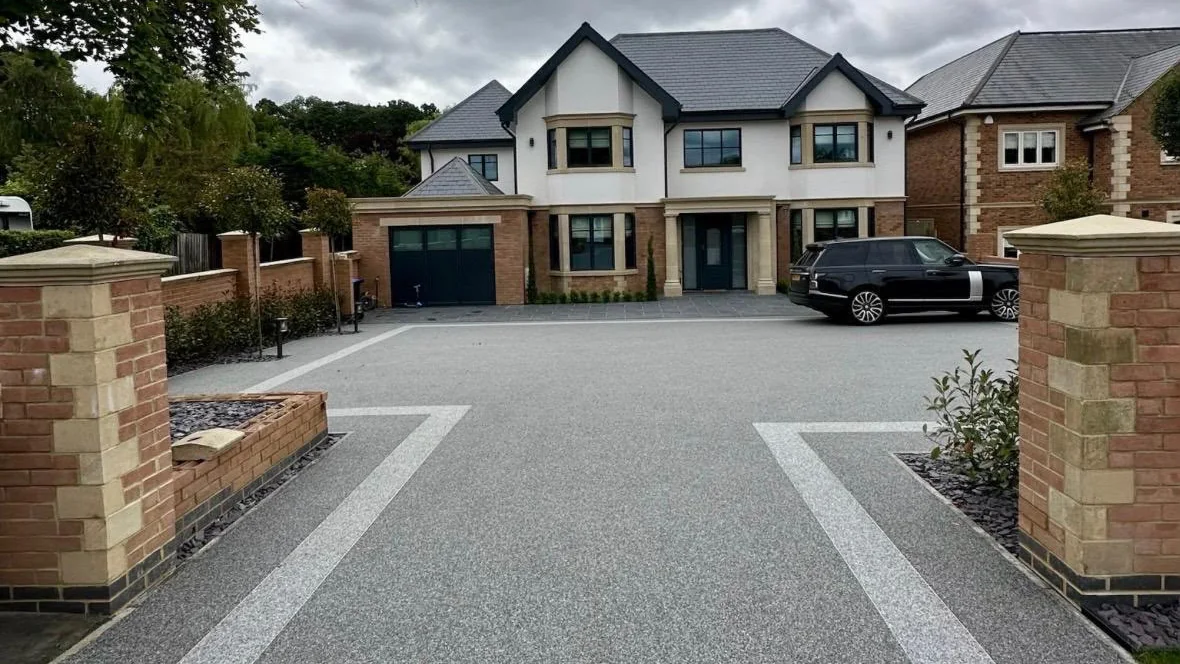 A sweeping silver resin bound driveway leading up to a large detached house